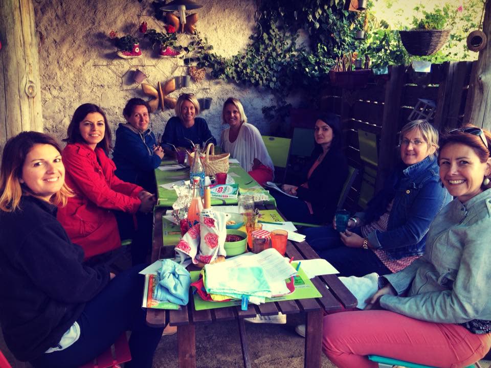 Des participantes souriantes autour d'une table dans un jardin